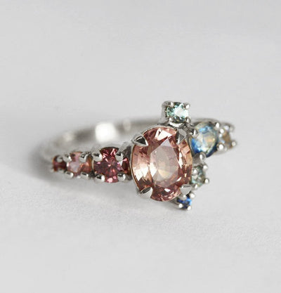 Oval-shaped peach sapphire and diamond cluster ring