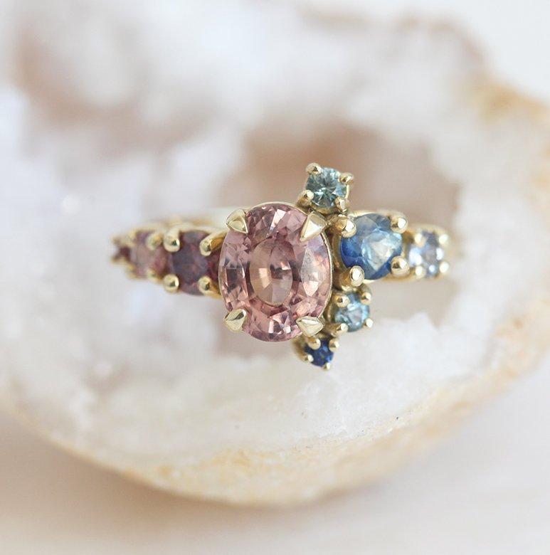 Oval-shaped peach sapphire and diamond cluster ring