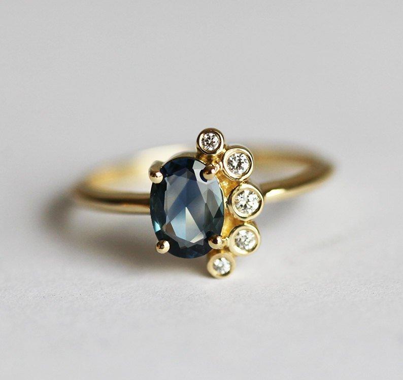 Oval-shaped sapphire cluster ring with side diamonds