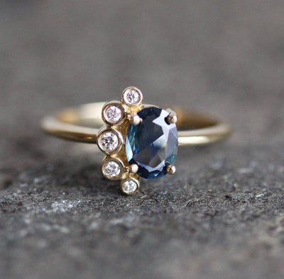 Oval-shaped sapphire cluster ring with side diamonds