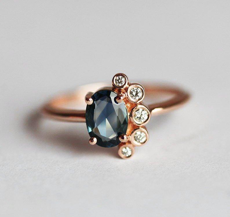 Oval-shaped sapphire cluster ring with side diamonds