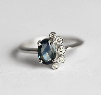 Oval-shaped sapphire cluster ring with side diamonds