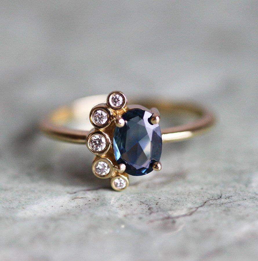 Oval-shaped sapphire cluster ring with side diamonds