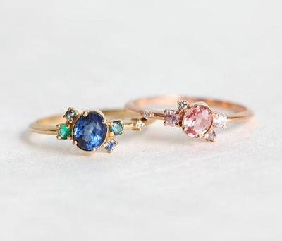 Blue oval sapphire ring with cluster diamonds and emeralds