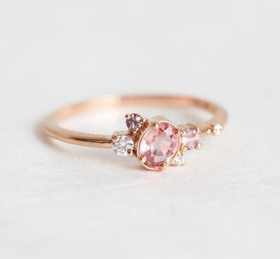 Oval-shaped pink-peach sapphire ring with diamond cluster