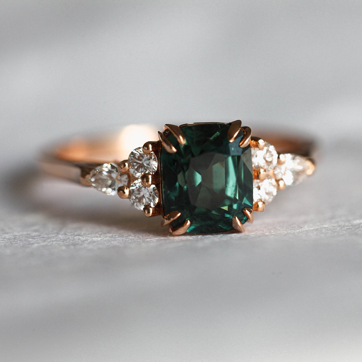 Cushion-cut teal sapphire cluster ring with diamonds