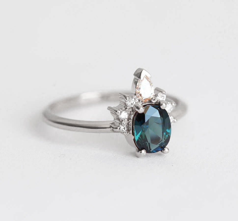 Teal oval-shaped sapphire ring with diamond halo