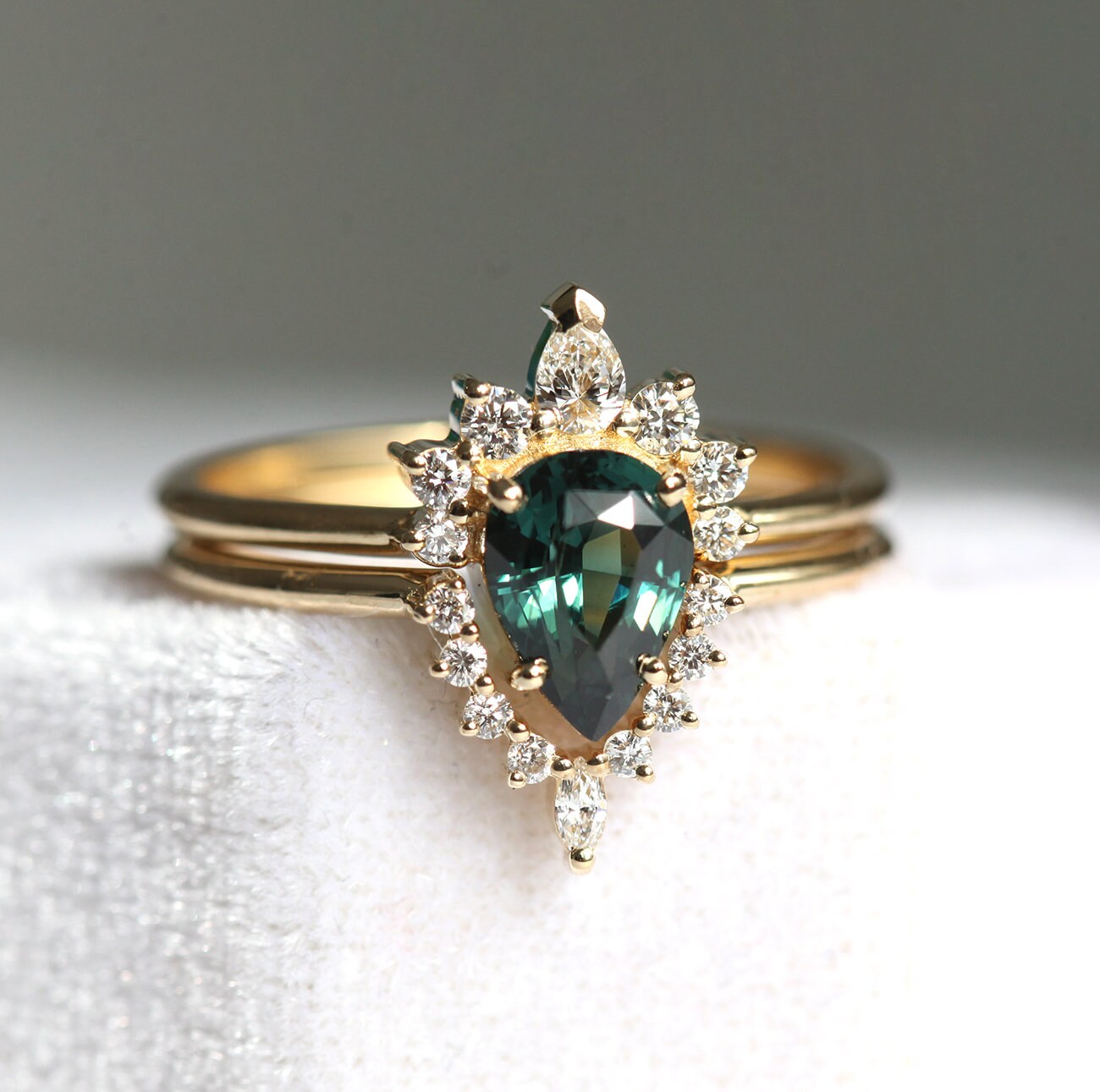 Pear-shaped teal sapphire ring with diamond halo