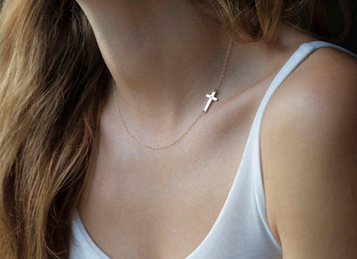 Gold cross necklace with round white diamond in center