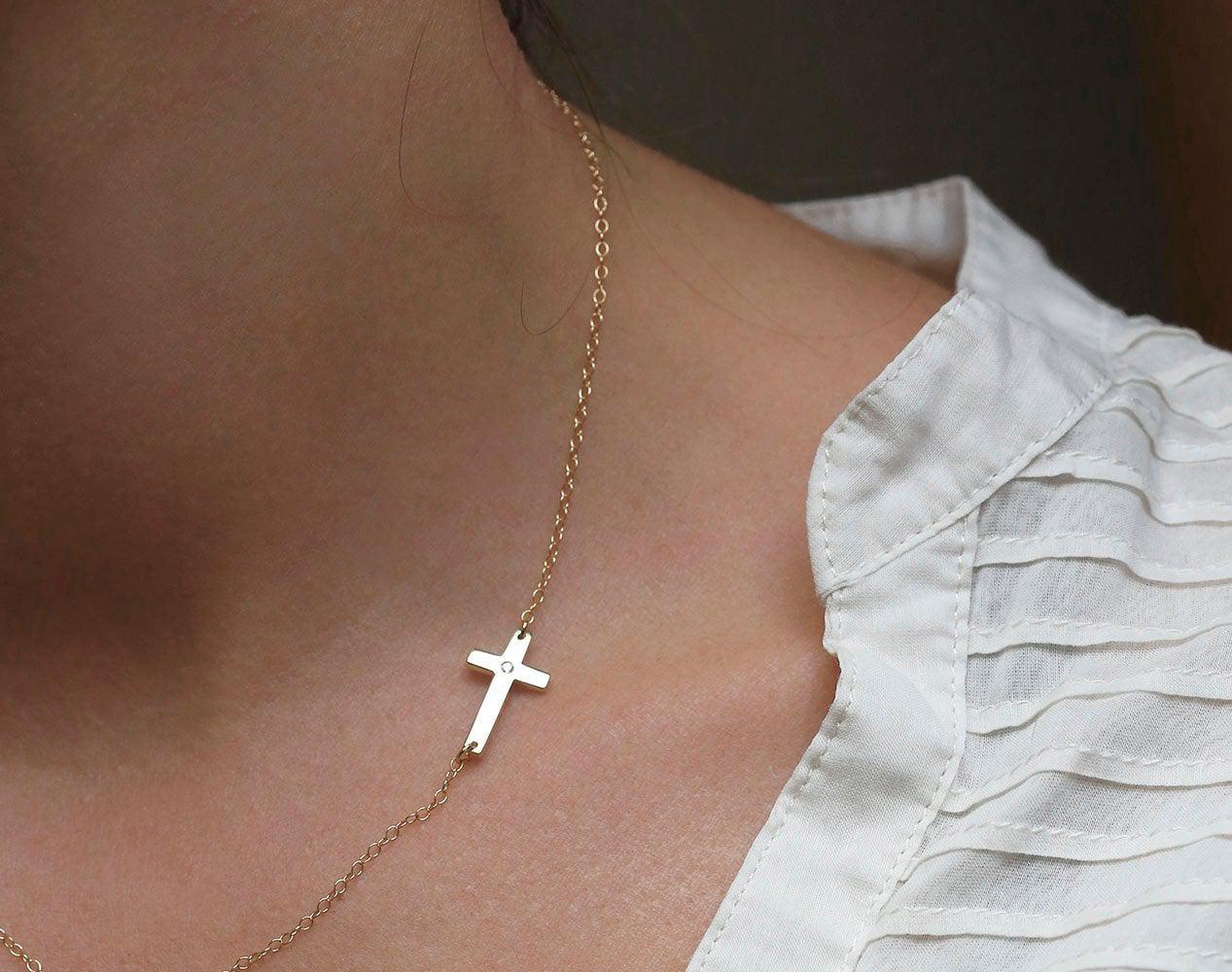 Gold cross necklace with round white diamond in center