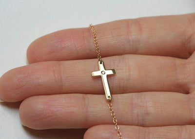 Gold cross necklace with round white diamond in center