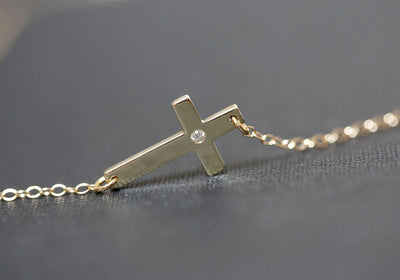 Gold cross necklace with round white diamond in center