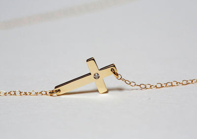 Gold cross necklace with round white diamond in center