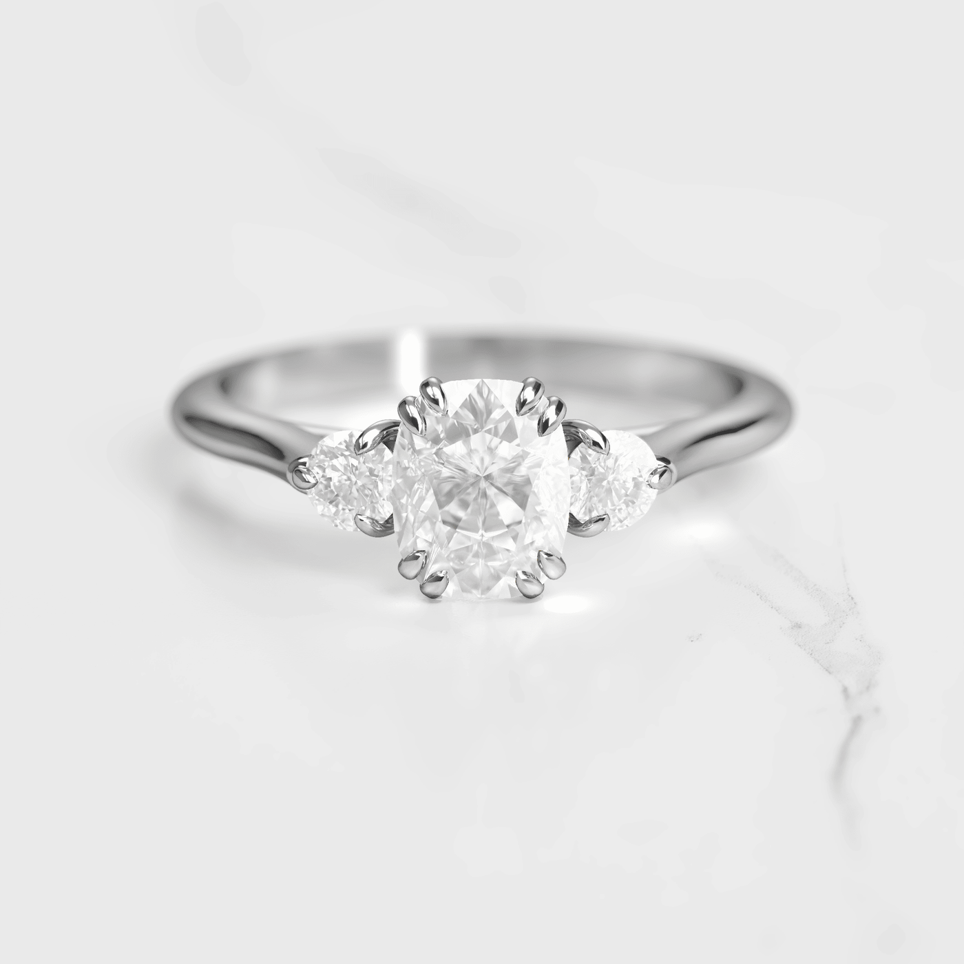 A 14k yellow gold engagement ring with a cushion-cut white diamond center stone and two round white diamond accent stones on either side