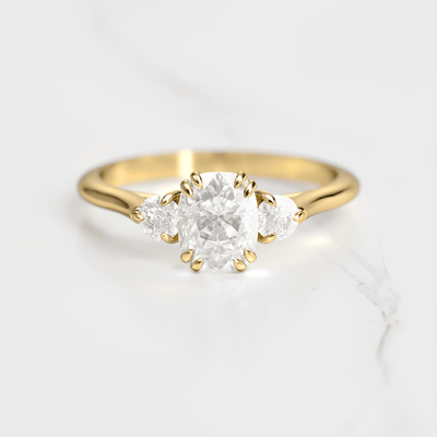A 14k yellow gold engagement ring with a cushion-cut white diamond center stone and two round white diamond accent stones on either side