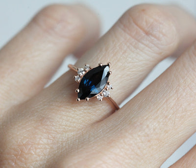 Marquise-shaped dark blue sapphire ring with white side diamonds