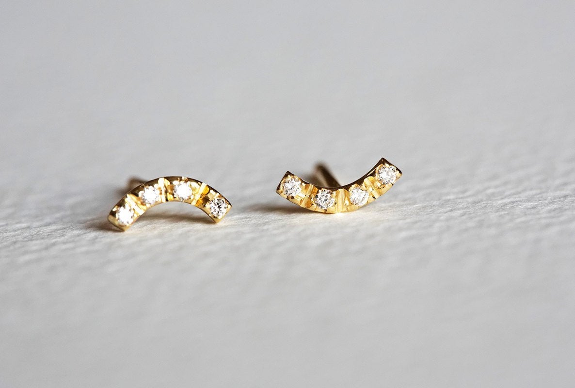 Round white diamonds on curved gold bar stud earrings