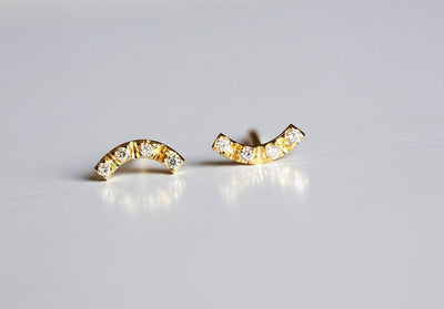 Round white diamonds on curved gold bar stud earrings