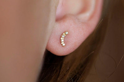 Round white diamonds on curved gold bar stud earrings