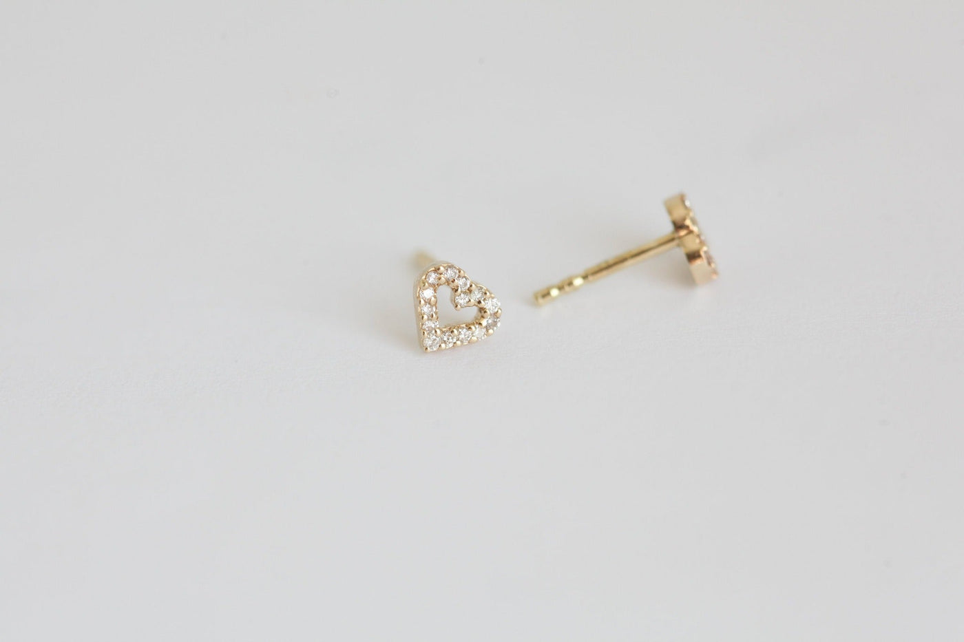 Heart-shaped gold stud earrings with round white diamonds