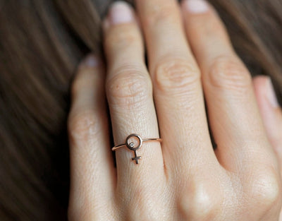 rose gold ring with a small round diamond in the center of a female symbol