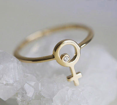 yellow gold ring with a small round diamond in the center of a female symbol