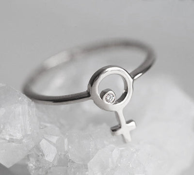 white gold ring with a small round diamond in the center of a female symbol