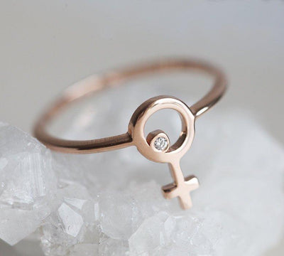 rose gold ring with a small round diamond in the center of a female symbol