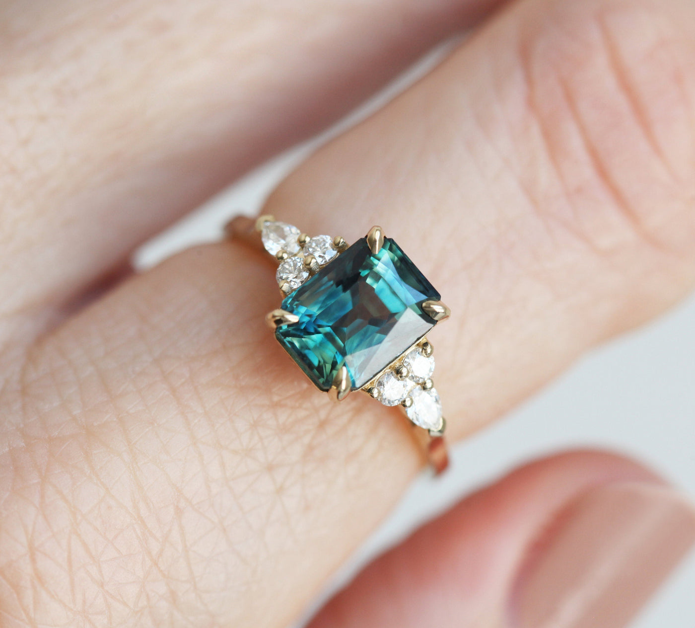 Radiant blue-green sapphire ring with side diamonds
