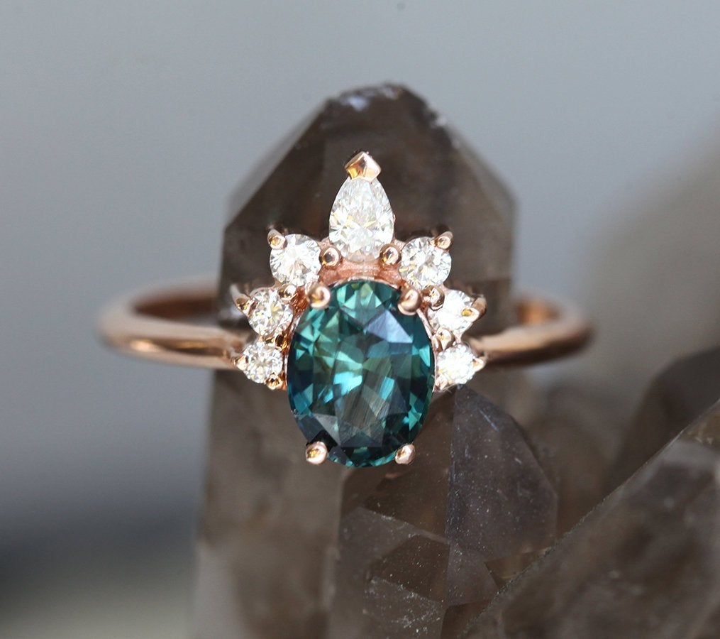 Oval teal sapphire ring with diamond halo
