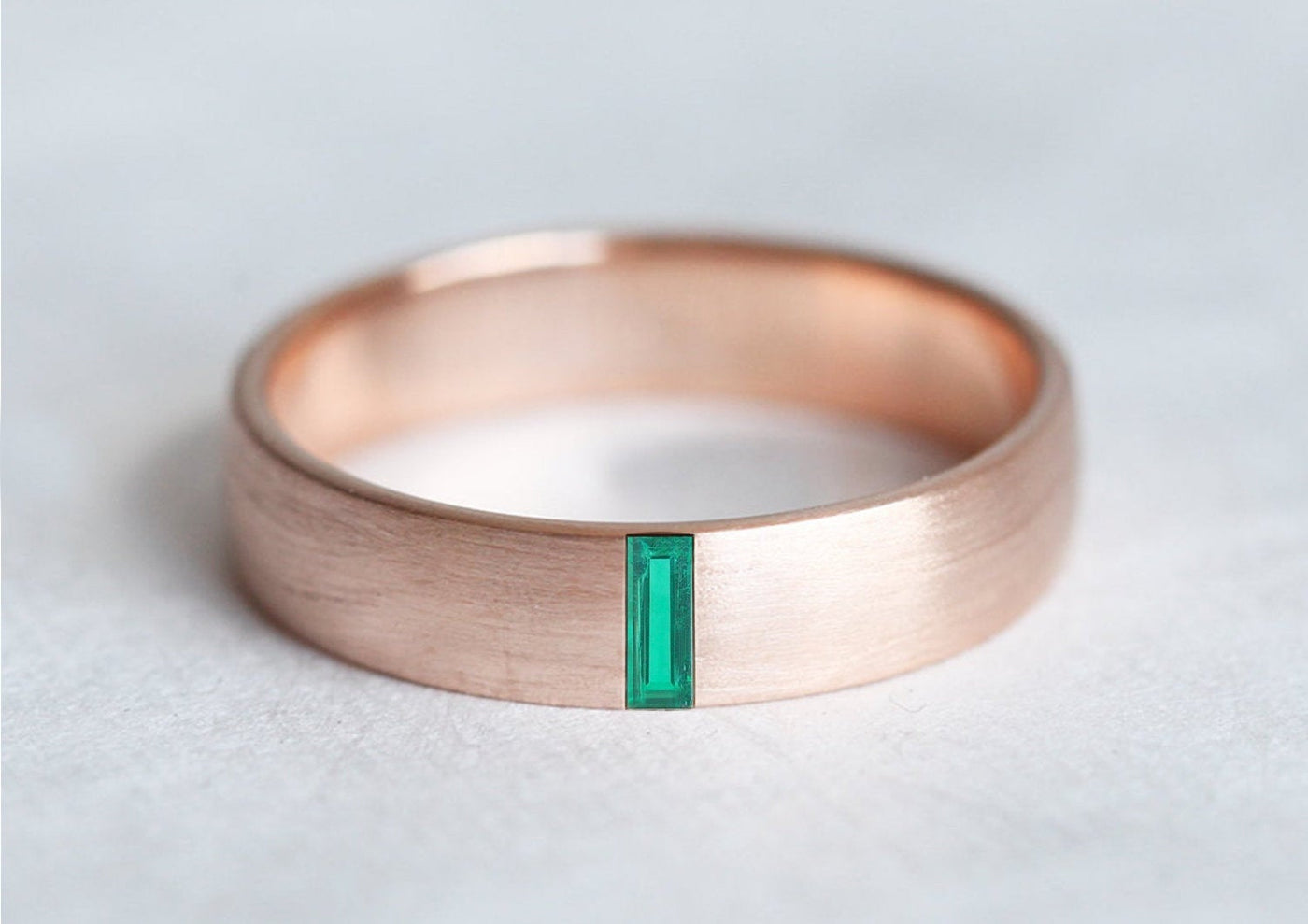 A stylish 4mm baguette Emerald band for weddings, featuring a green gem.