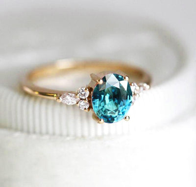 Oval teal sapphire ring with white side diamonds