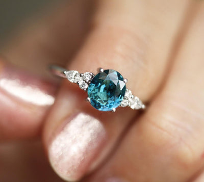 Oval teal sapphire ring with white side diamonds