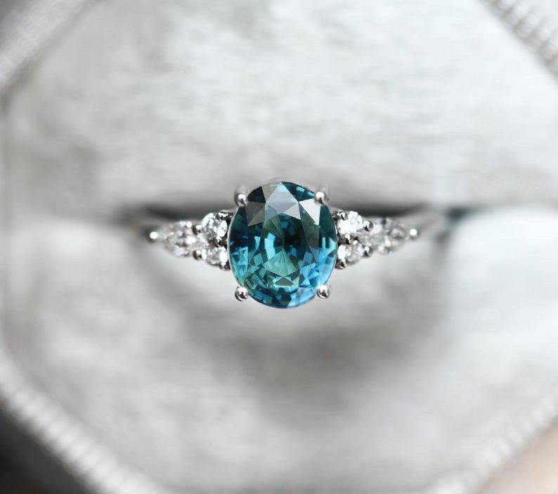 Oval teal sapphire ring with white side diamonds