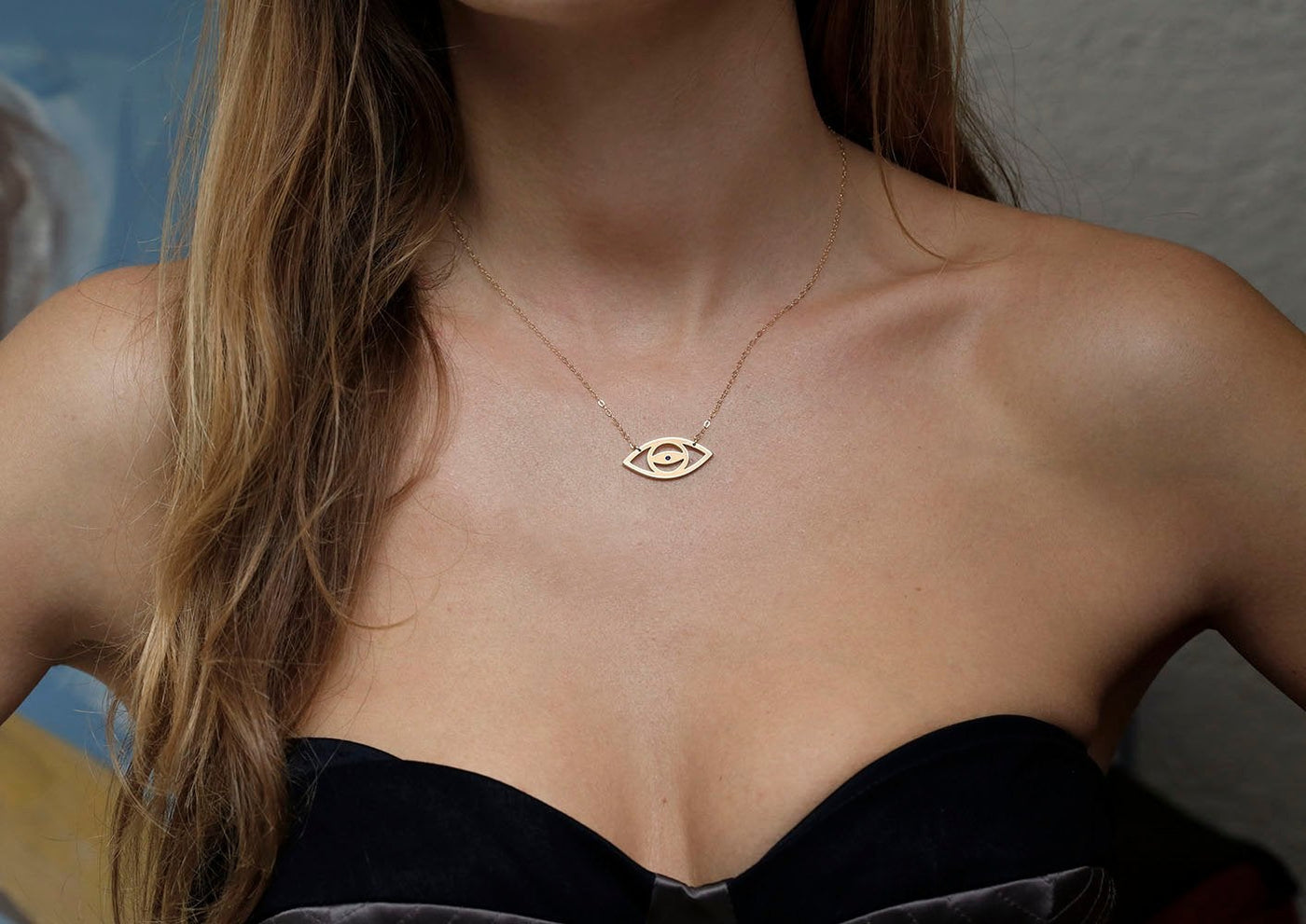 Gold eye silhouette necklace with round blue sapphire