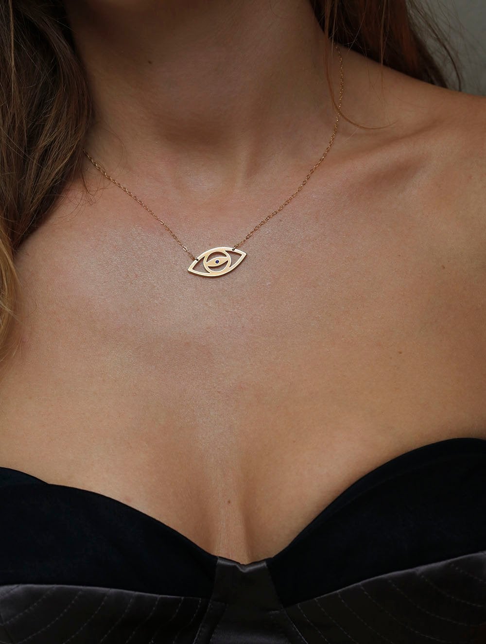 Gold eye silhouette necklace with round blue sapphire