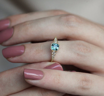 Blue emerald-shaped sapphire ring with white side diamonds