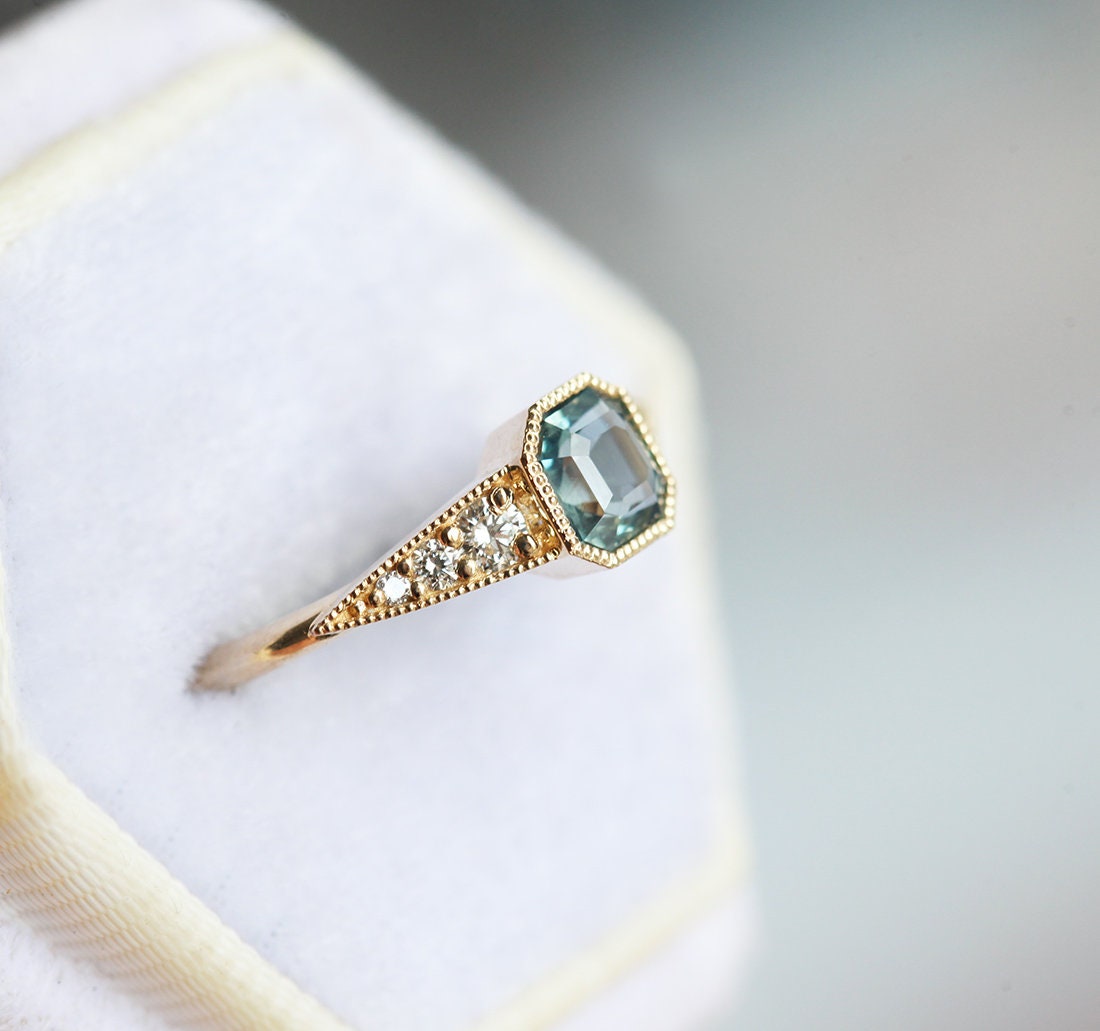 Blue emerald-shaped sapphire ring with white side diamonds