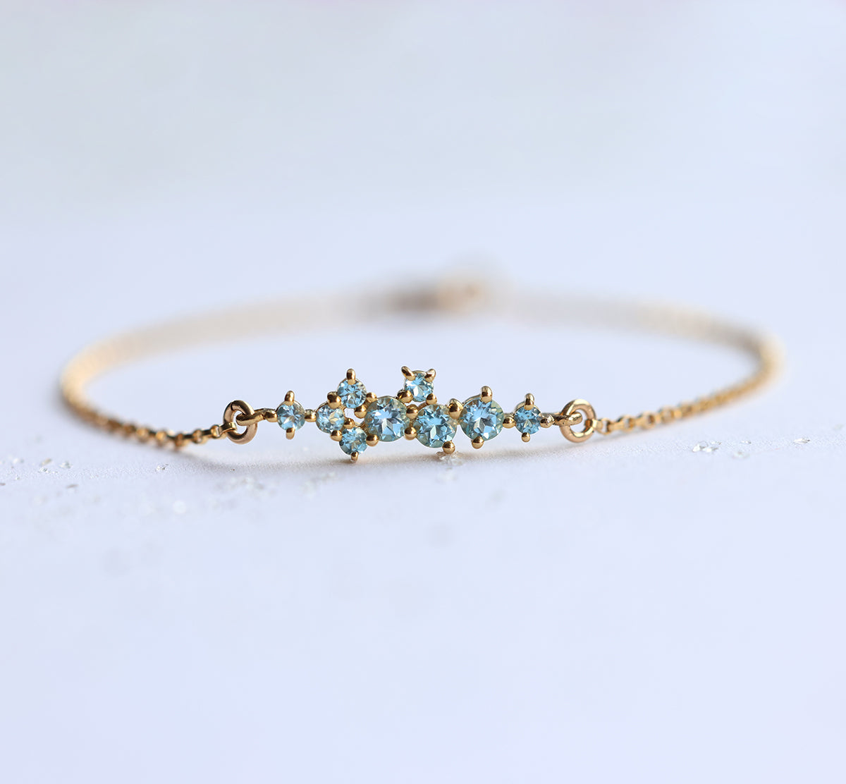 Gold chain bracelet with round blue topaz cluster