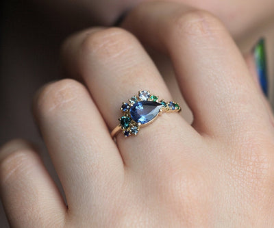 Pear-shaped blue sapphire cluster ring with diamond, topaz and emerald side stones