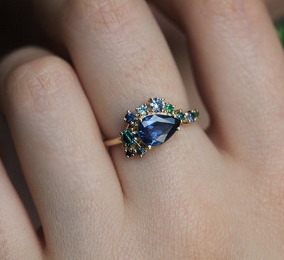 Pear-shaped blue sapphire cluster ring with diamond, topaz and emerald side stones