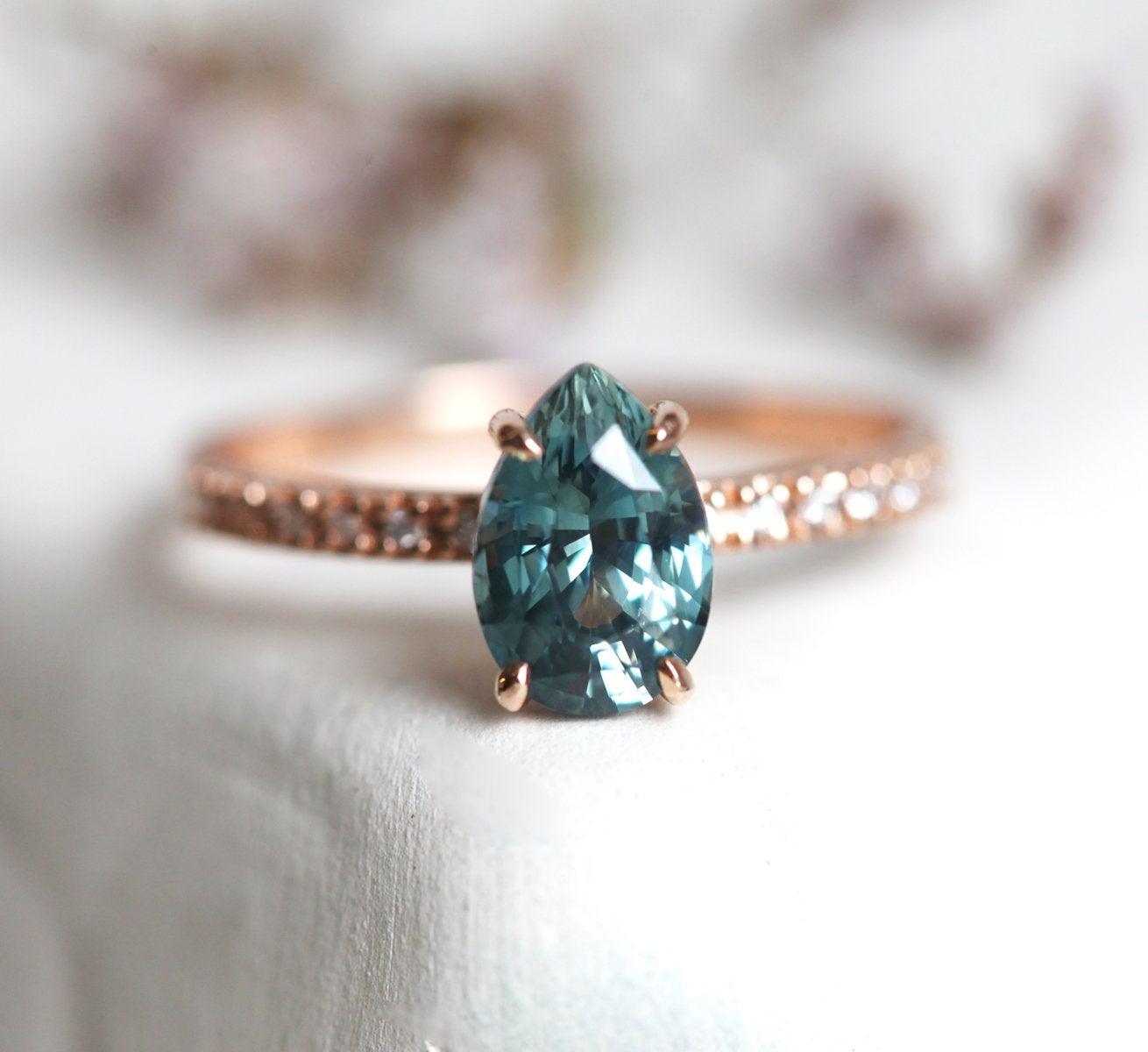 Pear-shaped teal sapphire ring with white side diamonds