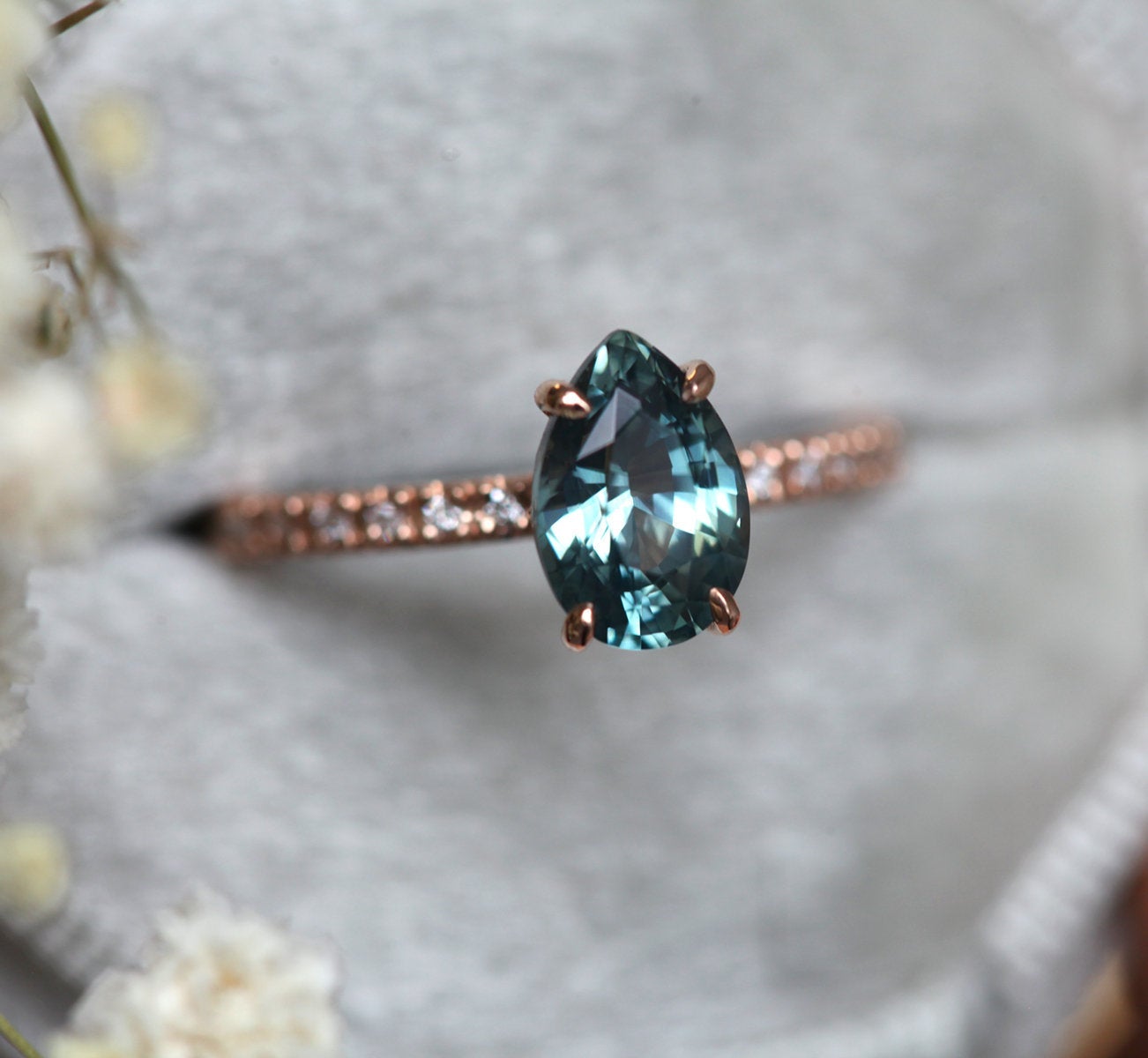 Pear-shaped teal sapphire ring with white side diamonds