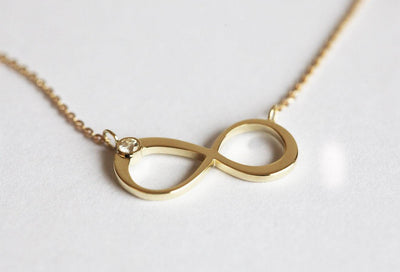 Infinity Symbol Gold Necklace with a Round White Diamond attached to the symbol