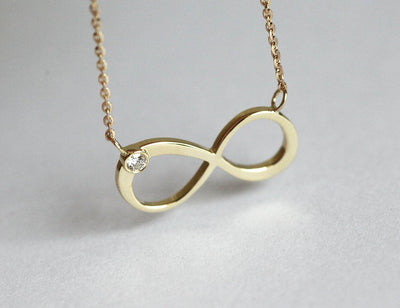 Infinity Symbol Gold Necklace with a Round White Diamond attached to the symbol