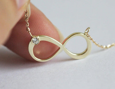 Infinity Symbol Gold Necklace with a Round White Diamond attached to the symbol