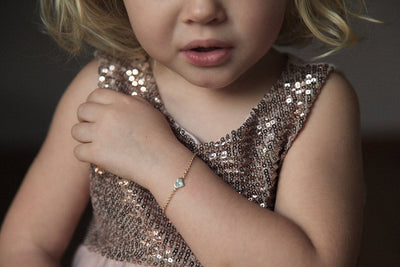Children's gold chain bracelet with heart charm and round white diamond