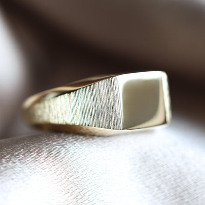 Gold signet ring on fabric, close-up of metal object, knife detail. Customizable, premium materials.