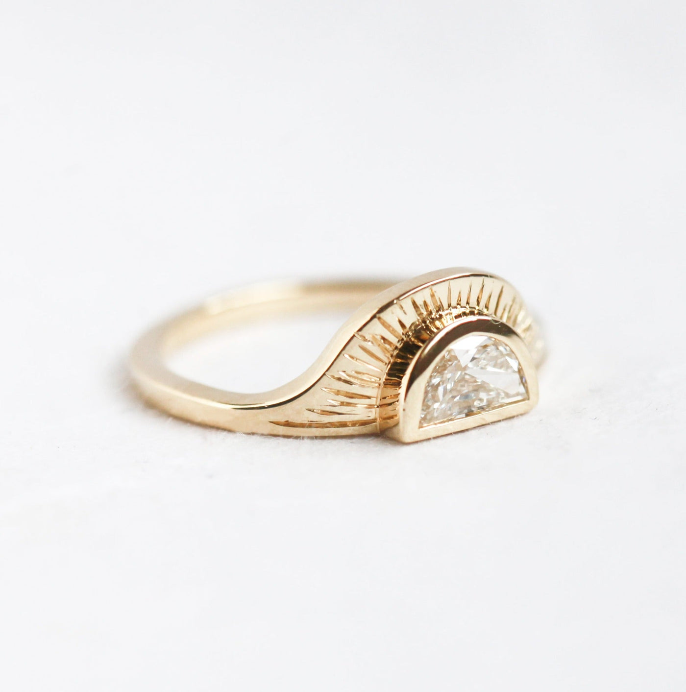 Unique 14k gold ring with a round white diamond in a half moon shape and sun rays engraved into the ring texture