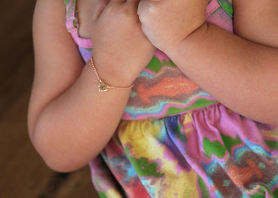 Infant's rose gold chain bracelet with heart charm and personalized initial letter